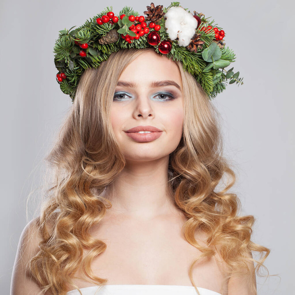 Kerstvrouw. Schattig model met make-up, schone frisse huid, golvend blond haar en kerstversiering - Foto, afbeelding