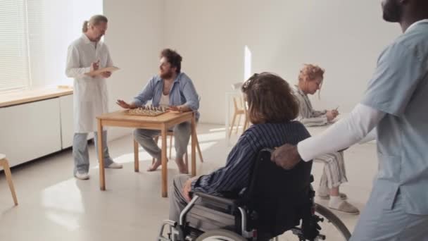 Africký americký muž zdravotní sestra přináší pacienta s duševní poruchou na jeho přítele, oni začínají šachovou hru - Záběry, video