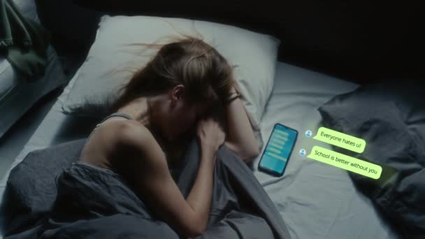 Directamente por encima de la foto de una adolescente acostada en la cama por la noche, recibiendo mensajes de los que odian en línea y llorando. CG texto animado apareciendo alrededor del teléfono móvil - Imágenes, Vídeo