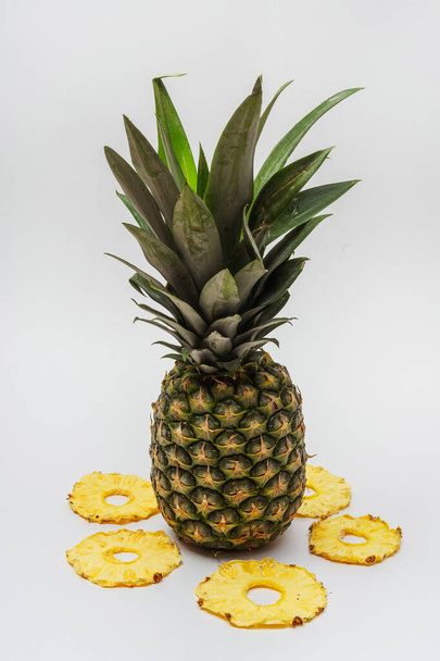Beyaz arka planda kurumuş ananas dilimleri. Kurutulmuş ananas suyu yemek ve içmek için. Hafif arkaplanda ananas parçaları - Fotoğraf, Görsel
