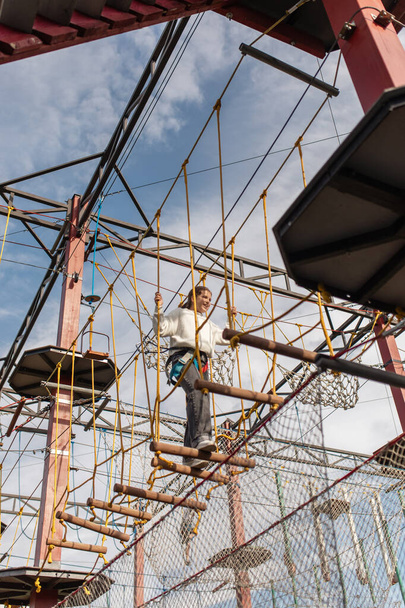 una adolescente feliz pasa obstáculos en un parque de cuerdas suspendidas. el concepto de recreación activa - Foto, Imagen