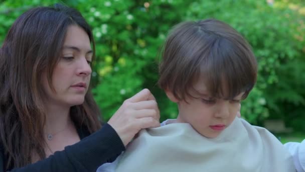 Mutter sichert Serviette am Halsband des Kindes für Sauberkeit beim Essen - Filmmaterial, Video