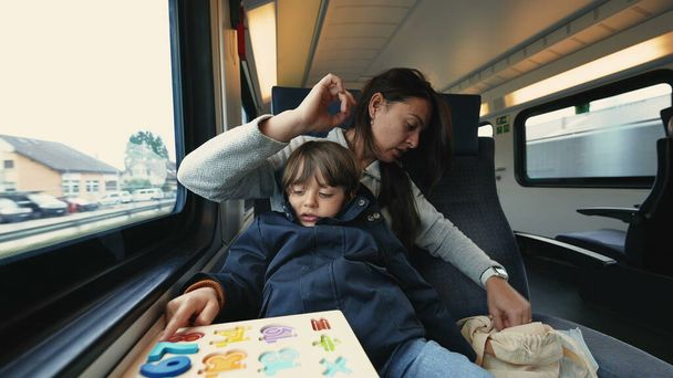 Matka i dziecko podróżujące pociągiem dużych prędkości i wykonujące zajęcia szkolne, aby spędzić czas - Zdjęcie, obraz