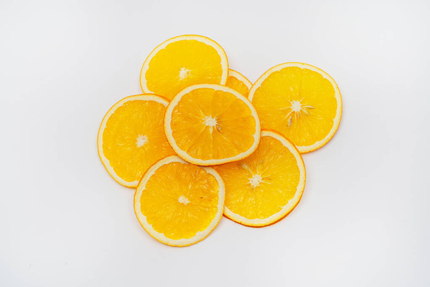 rebanadas de naranja seca sobre un fondo blanco. naranja secada en un deshidratador para preparar alimentos y bebidas. chips de naranja sobre un fondo claro - Foto, imagen