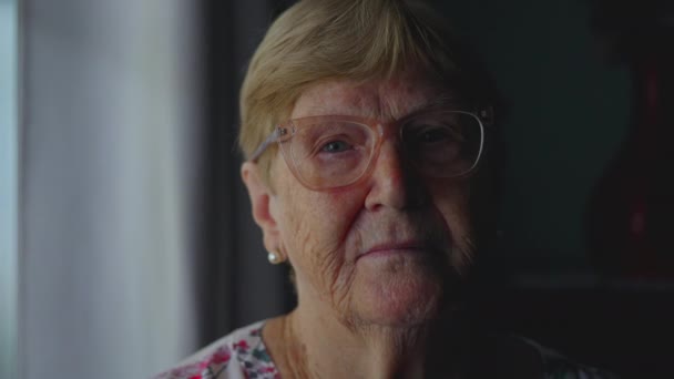 Close-up van oudere vrouw met ernstige expressie kijkend naar camera, dramatische verlichting Accentuerende ervaring en ouderdom - Video