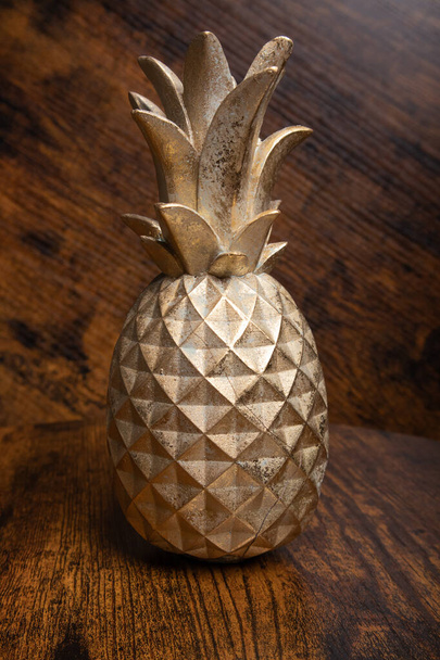 abacaxi decorativo, close-up de uma figura de metal decorativo na forma de um abacaxi em um fundo de madeira - Foto, Imagem