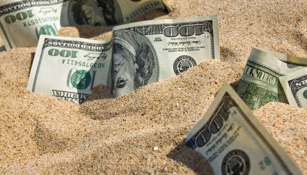 Dólares en arena en una playa
 - Foto, imagen