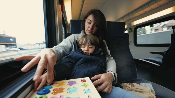 Matka i dziecko podróżujące pociągiem dużych prędkości i wykonujące zajęcia szkolne, aby spędzić czas - Zdjęcie, obraz