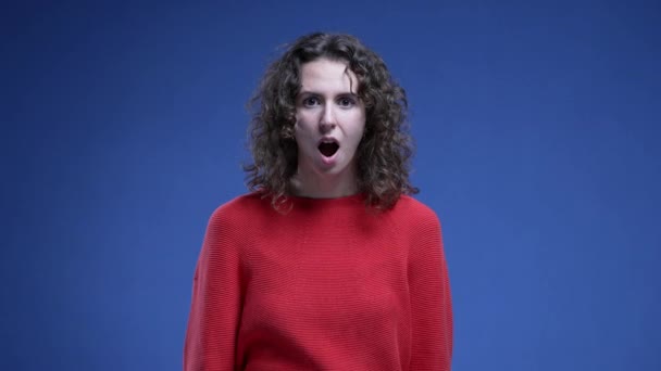 Žena zakrývající ústa v SHOCK a nevěřícně hledící přímo do kamery. žena ve 20s pokrývá ústa v překvapení reagující na neuvěřitelné zprávy - Záběry, video