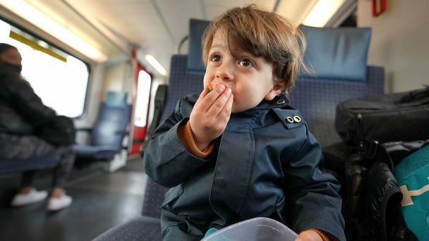 Молодой путешественник хватается за контейнер с ягодами, наслаждается питательным фруктовым укусом, садится в движущийся поезд, перекусывает по пути - Фото, изображение