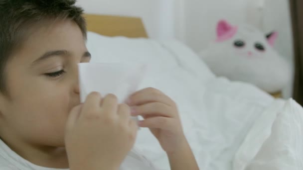 Enfant garçon caucasien dans le lit se sentant mal à l'aise souffler son symptôme du nez pour le rhume ou la bronchite. Concept de soins de santé. Au ralenti. Images 4k de haute qualité - Séquence, vidéo