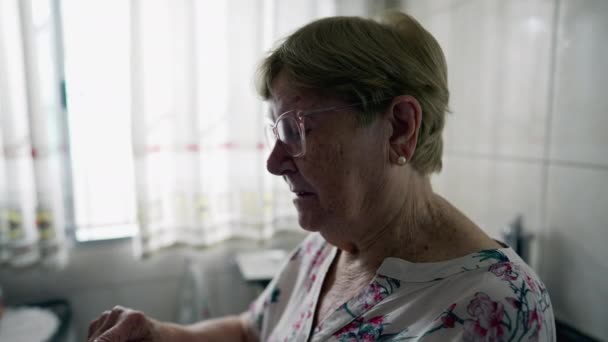 Profil-Nahaufnahme einer älteren Frau, die mit ihrem Smartphone zu Hause scrollt. Ehrlicher häuslicher Lebensstil älterer Menschen mit Technologie - Filmmaterial, Video