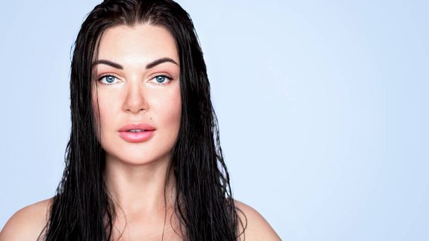 Beautiful girl, woman with dark wet hair. Smiling. Blue eyes. on a blue background. - Photo, Image