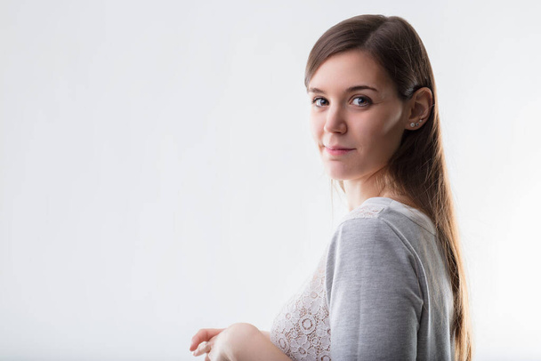 Kontemplativní mladá žena v krajkou zdobené košili, nabízející záblesk klidné jistoty - Fotografie, Obrázek
