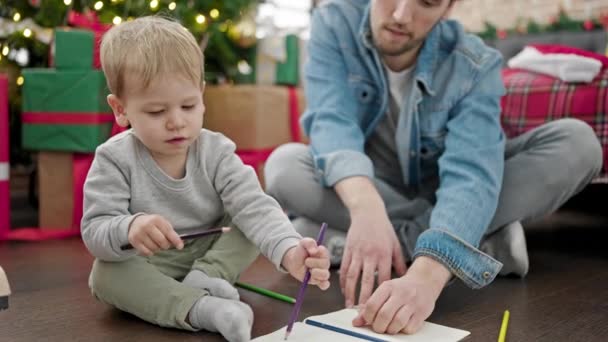 Padre e hijo celebrando el dibujo de Navidad en el cuaderno en casa - Imágenes, Vídeo