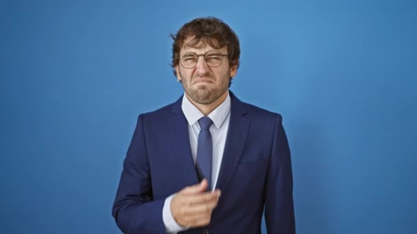 Junger Mann im Anzug ekelt sich vor unerträglichem Gestank, hält den Atem an, kneift die Nase, um dem übelriechenden Gestank über isoliertem blauem Hintergrund zu entkommen - Filmmaterial, Video