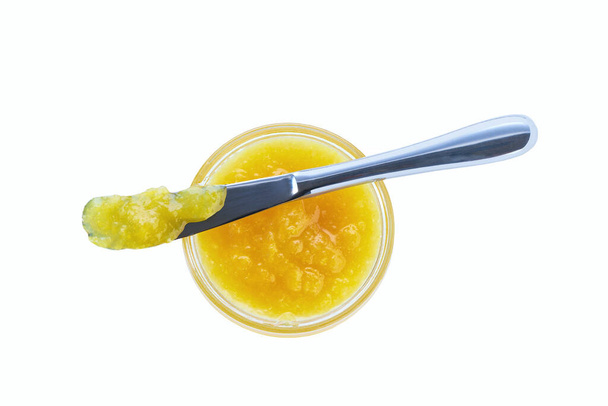 Horní pohled na citrónovou marmeládu ve sklenici s nožem izolovaným na bílém pozadí. Sklenice citrónové konfitury s nožem horní pohled, izolované na bílém pozadí. - Fotografie, Obrázek