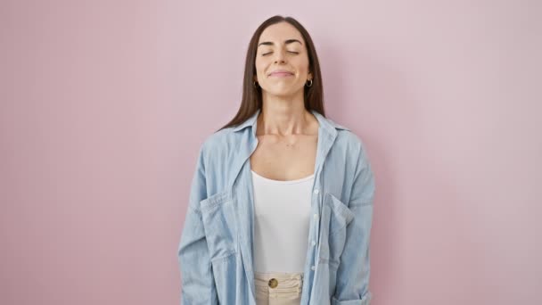 Потрясающая молодая латиноамериканка в повседневной одежде находит дзен на розовом фоне, закрытые глаза медитации с жестом пальца йоги, красивое путешествие к расслаблению и внимательности - Кадры, видео