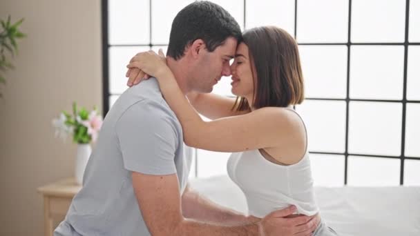 Casal bonito abraçando uns aos outros sentado na cama beijando no quarto - Filmagem, Vídeo