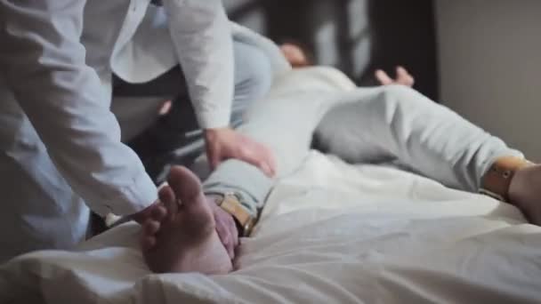 Travailleur médical mature attachant un patient agressif souffrant de troubles mentaux au lit d'hôpital avec utilisation de ceintures - Séquence, vidéo