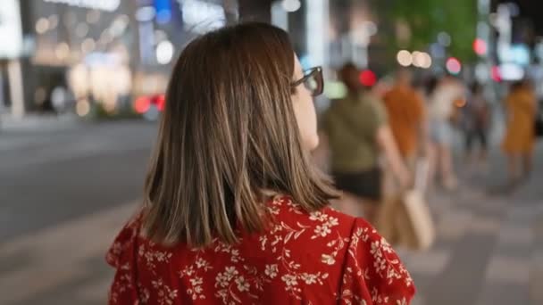 Schöne hispanische Frau mit Brille, die davonläuft, sich in den nächtlich beleuchteten Tokyostraßen umsieht und legeres Charisma ausstrahlt - Filmmaterial, Video