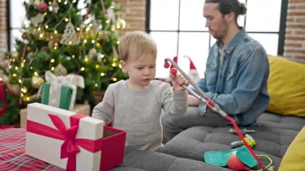 Padre e figlio disimballano il regalo di Natale usando il laptop a casa - Filmati, video