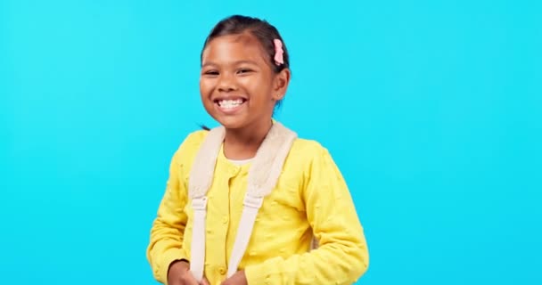 School, portrait of girl and excited student with backpack, bag or motivation for learning or education on blue background. Child laughing, kid with smile and happiness to study knowledge in studio. - Footage, Video