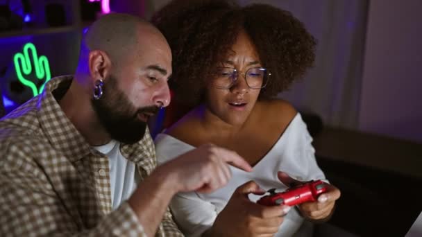 Deux joueurs, un homme et une femme, plongés dans une séance de jeu vidéo sérieux. jouer ensemble, rire et expliquer les stratégies dans la salle de jeux sombre, streaming de leur divertissement virtuel en ligne. - Séquence, vidéo
