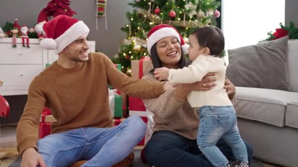 Ζευγάρι και γιος κρατώντας μπάλα διακόσμηση κάθεται στο πάτωμα από χριστουγεννιάτικο δέντρο στο σπίτι - Πλάνα, βίντεο