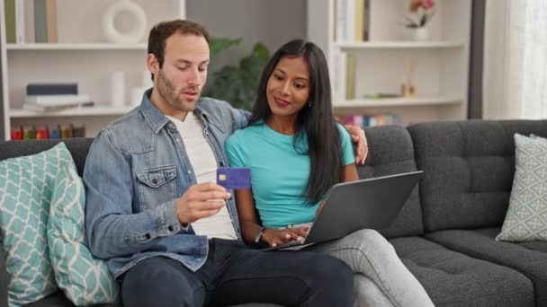 Beautiful couple shopping with laptop and credit card sitting on sofa at home - Footage, Video