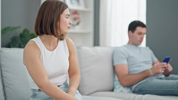 Belo casal sentado no sofá silencioso com problema usando smartphone em casa - Filmagem, Vídeo
