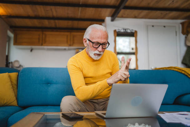 Un anziano uomo caucasico nonno con barba e occhiali lavora sul computer portatile usa computer a casa videochiamata online - Foto, immagini