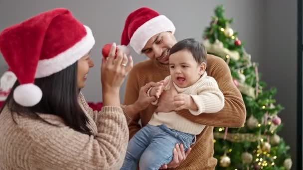 Paar en zoon houden decoratie bal stand-by kerstboom thuis - Video