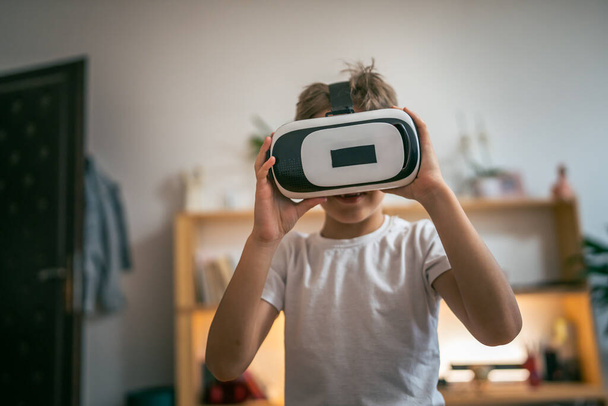 chłopiec mężczyzna kaukaski dziecko w domu korzystaj wirtualna rzeczywistość VR zestaw słuchawkowy - Zdjęcie, obraz