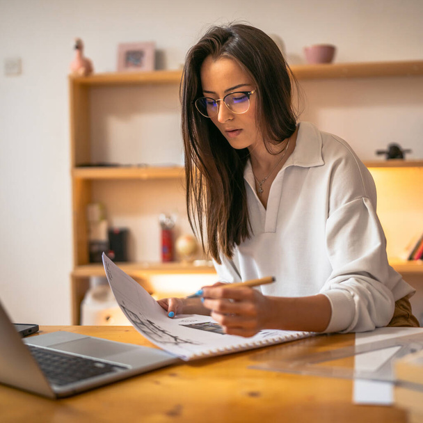 młody kaukaski kobieta nauka przed laptop komputer w domu - kobieta czytanie książki przygotowanie egzamin lub zadanie test po konsultacji online - edukacja i nauka pojęcie - Zdjęcie, obraz