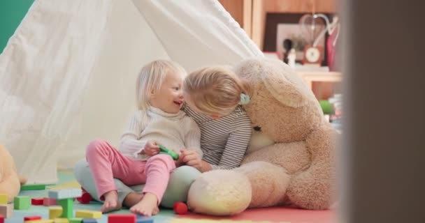 Kubus, meisje en broers en zussen met lachen op de vloer voor de lol of onderwijs thuis met teddybeer. Geluk, kind en zussen spelen met speelgoed voor bond in huis met stabiliteit voor kwaliteit tijd - Video