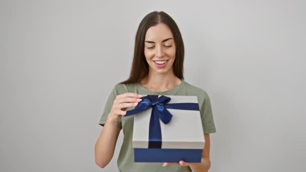 Vidám fiatal spanyol nő magabiztosan tartja a születésnapi ajándékát, egy diadalmas "oké" táblát villantva az ujjaival, mosolyogva és pozitívan ragyogva egy elszigetelt fehér falon.. - Felvétel, videó