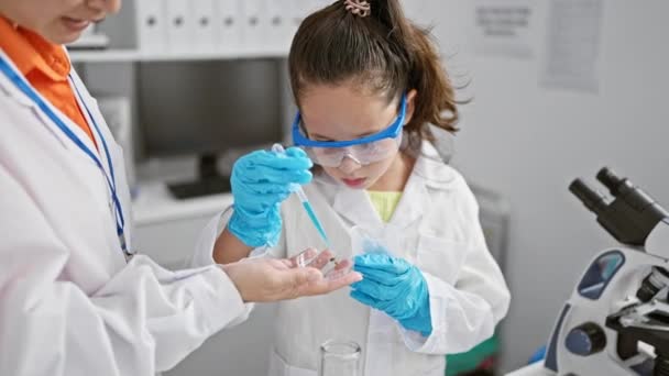 Dos científicos apasionados trabajando juntos, sumergiéndose en la investigación, vertiendo muestras líquidas en un laboratorio bullicioso, gafas de seguridad en - Metraje, vídeo