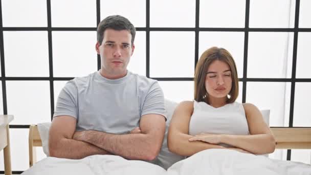 Belo casal sentado na cama com braços cruzados gesto olhando chateado no quarto - Filmagem, Vídeo