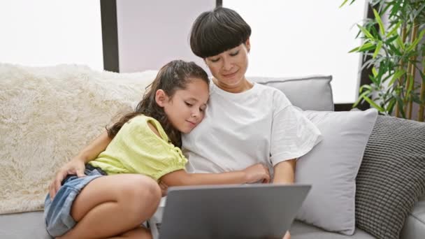 Moeder en dochter delen een liefdevolle kus op de bank thuis, terwijl gelukkig met behulp van laptop, verdiept in een feel-good familie film - Video