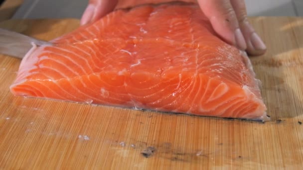 De chef snijdt een filet verse rode vis met een mes. Kook zalm rauw vlees voor steak slow motion close-up zicht. - Video