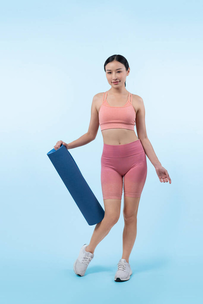 Jeune femme asiatique attrayant portrait en vêtements de sport avec tapis d'exercice. Exercice sain et routine d'entraînement concept de mode de vie. Studio a tourné en arrière-plan isolé. Vigoureux - Photo, image
