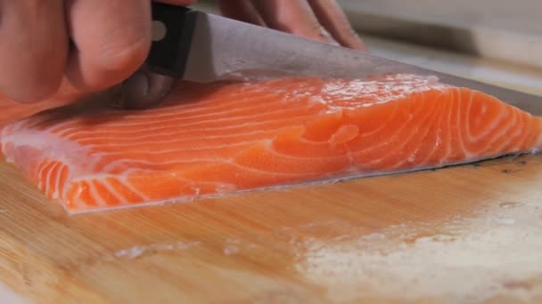 De chef snijdt een filet verse rode vis met een mes. Kook zalm rauw vlees voor steak slow motion close-up zicht. - Video