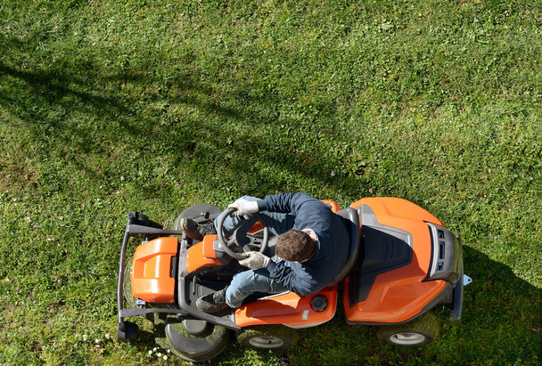 Un homme fauchant une pelouse sur une tondeuse à gazon
 - Photo, image