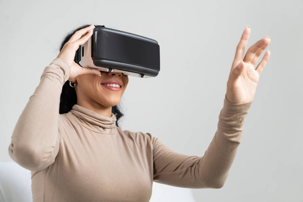 Jeune femme utilisant réalité virtuelle VR masque à la maison pour une expérience d'achat en ligne cruciale. L'innovation VR en réalité virtuelle optimisée pour le divertissement numérique féminin. - Photo, image
