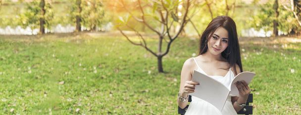 Bannerfrau mit Buch-Lesezeitschrift im grünen Park Naturgarten. Entspannte junge Frau las offenes Buch zum Selbststudium. Glückliche Universitätsfrauen lächeln. Frauen sitzen im grünen Park mit Kopierraum - Foto, Bild