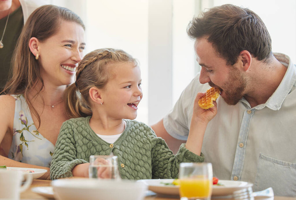 Breakfast, family and eating with parents, mother and happy kid together in a home. Love, support and care on a dining room with a smile and food with bonding in the morning with waffle in a house. - Photo, Image