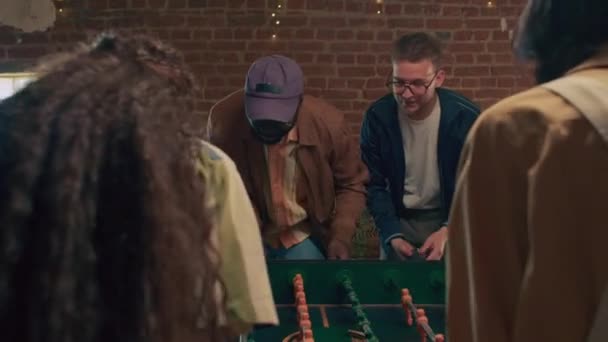 テーブルサッカーゲームのラウンドで勝った若い黒人と白人男性の選択的な焦点ショット - 映像、動画