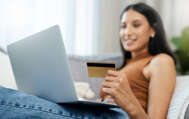 Laptop, Kreditkarte und Frau auf dem Sofa für Online-Shopping, E-Commerce und digitales Bezahlen oder Bestellen zu Hause. Entspannen Sie sich am Computer mit Internet-Banking, Sicherheitsnummern oder der Registrierung für einen Kredit. - Foto, Bild
