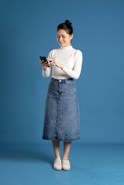 Imagen de una hermosa mujer asiática posando sobre fondo azul - Foto, Imagen